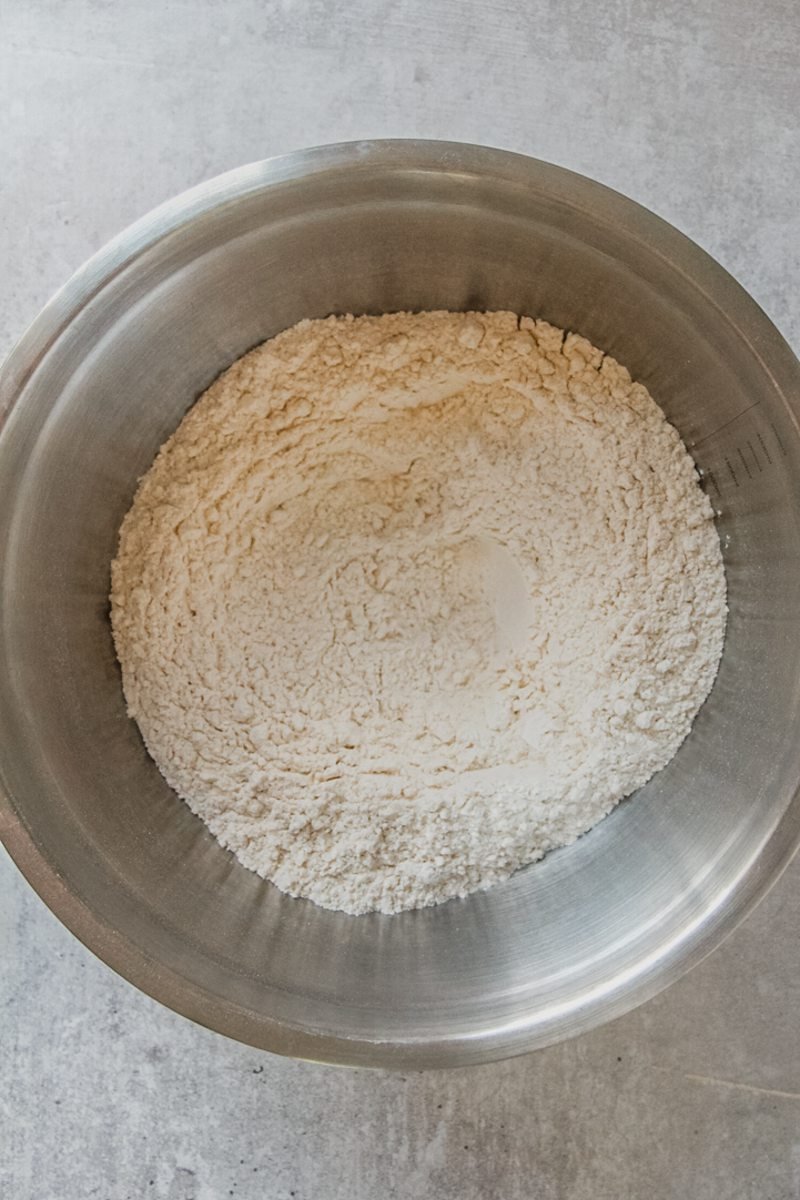 A dry mixture sits in a stainless steel bowl on a gray surface.