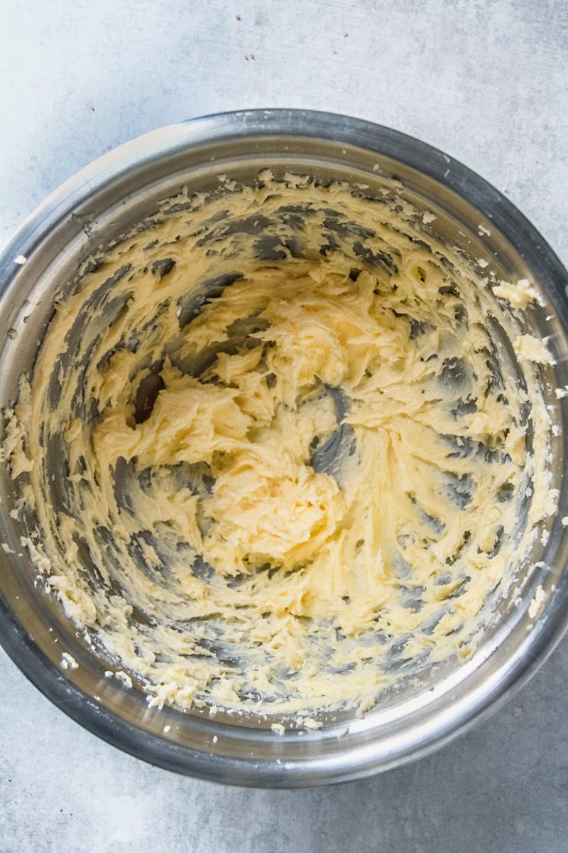 Whipped butter sits in a stainless steel bowl on a gray surface.