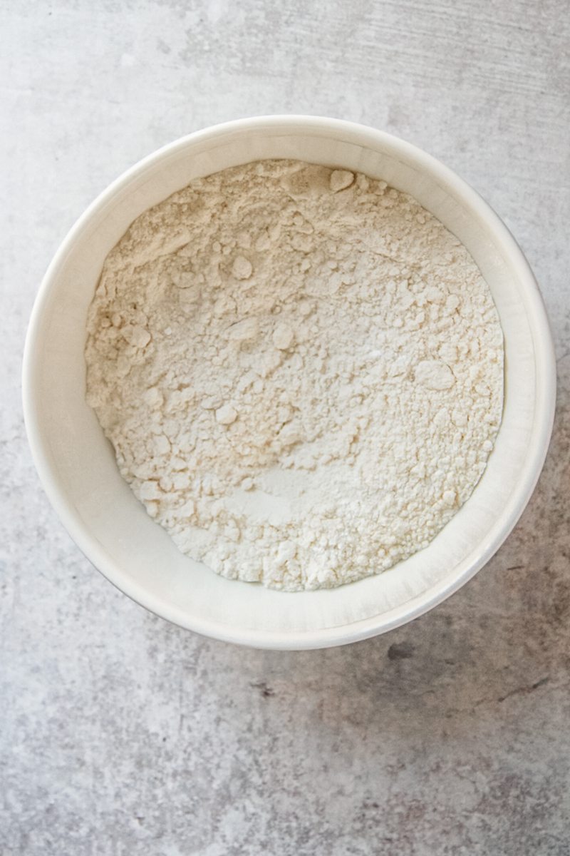 Dry ingredients sit in a white ceramic bowl on a gray surface.