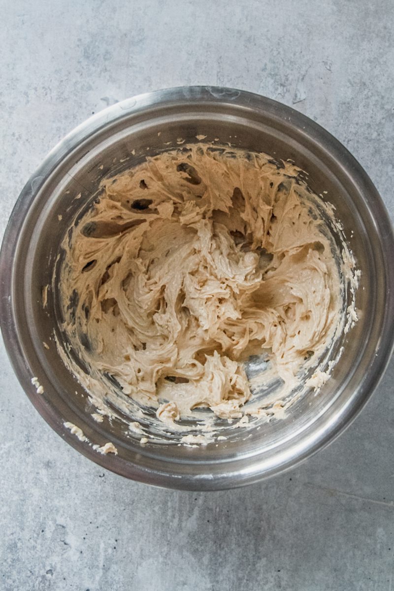 Whipped cookie dough sits in a stainless steel bowl on a gray surface.