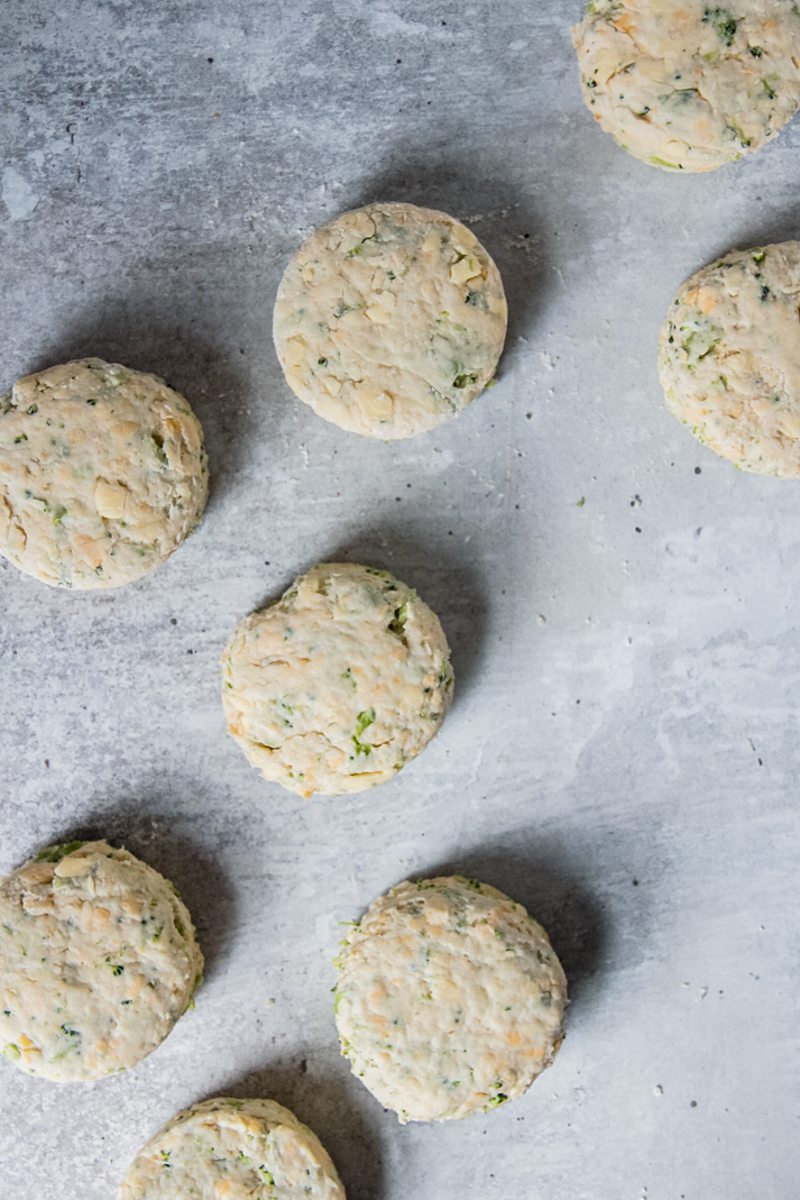 Cheddar and broccoli biscuits sit on a gray surface.