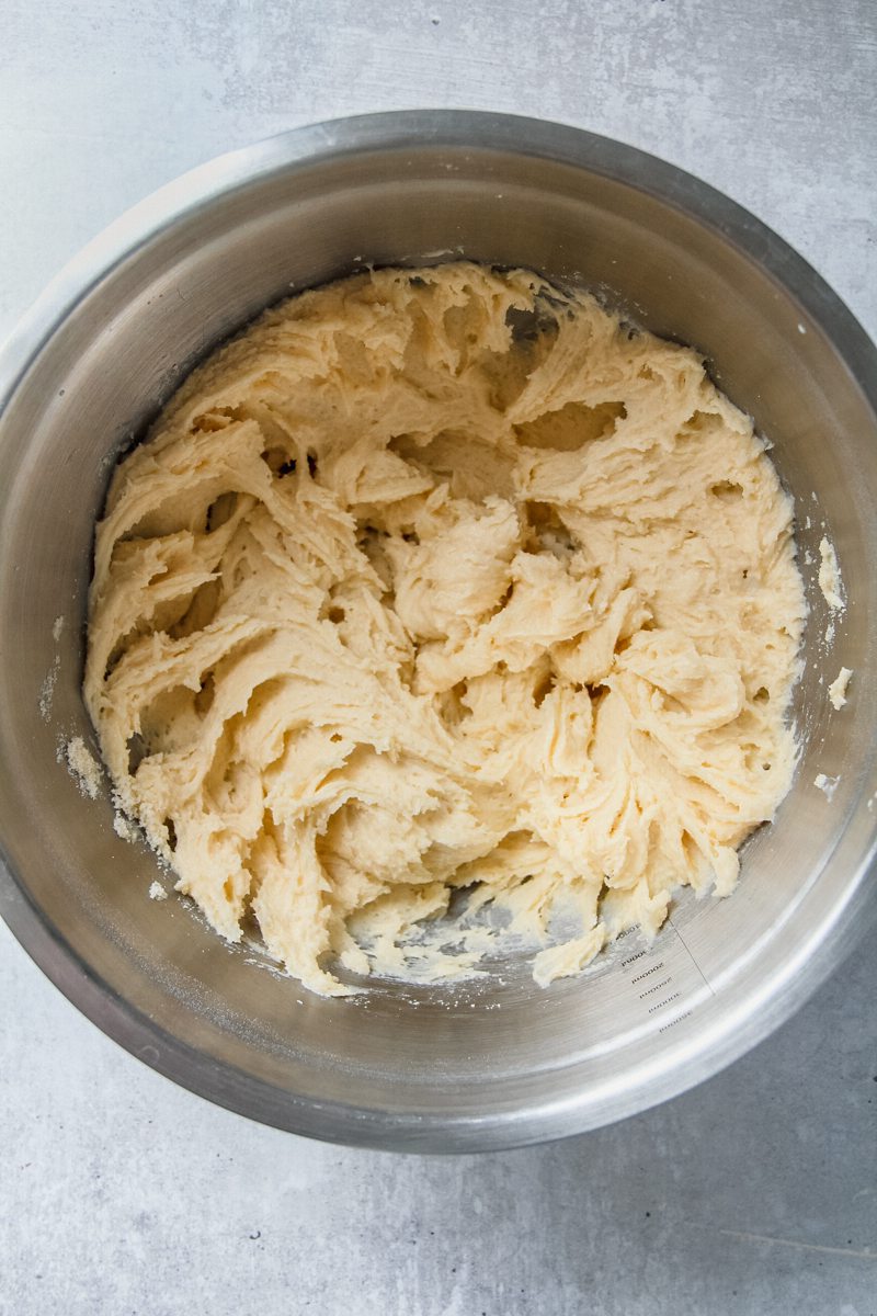 Whipped cake batter sits in a stainless steel bowl on a gray surface.