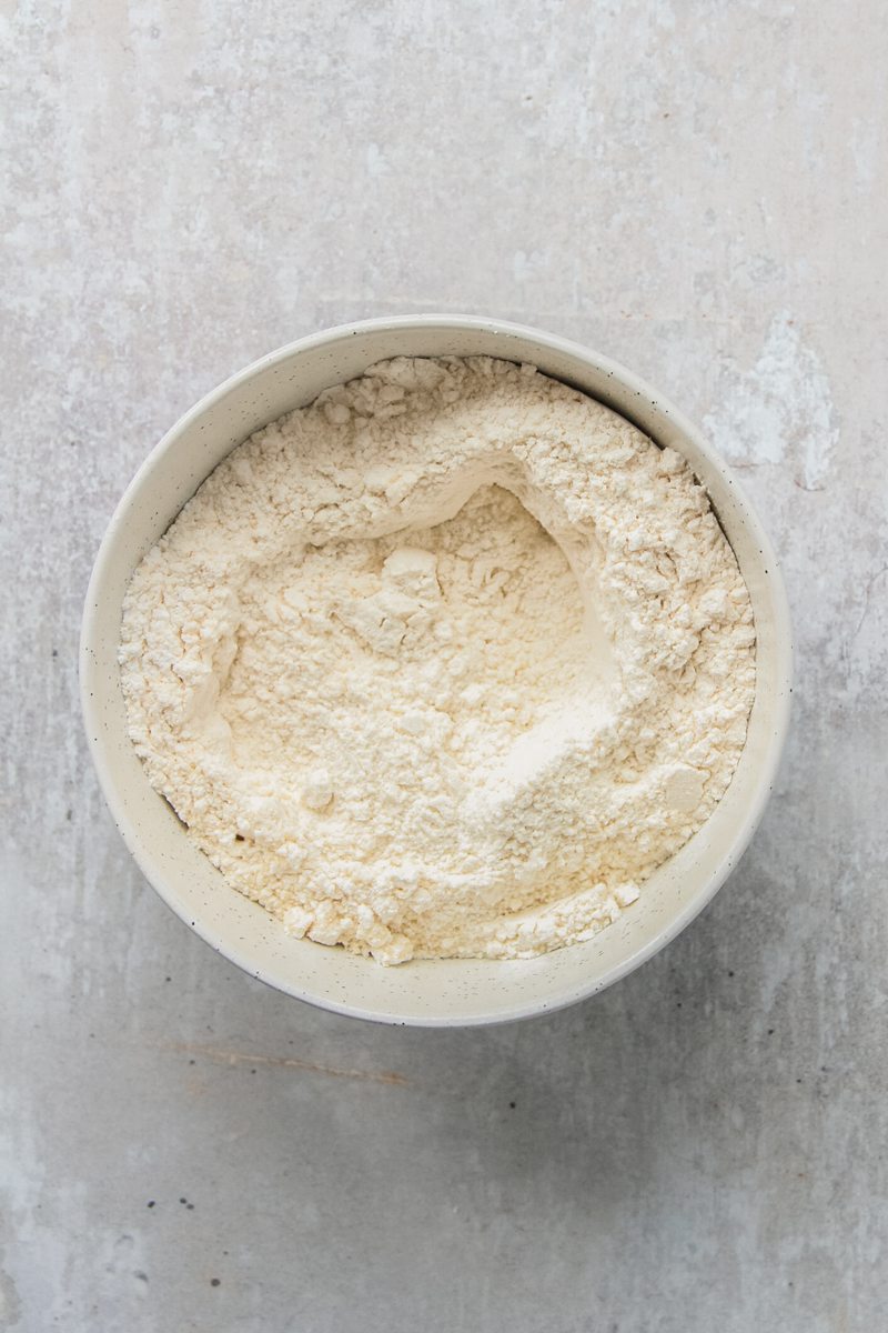 Dry ingredients sit in a white ceramic bowl on a gray surface.