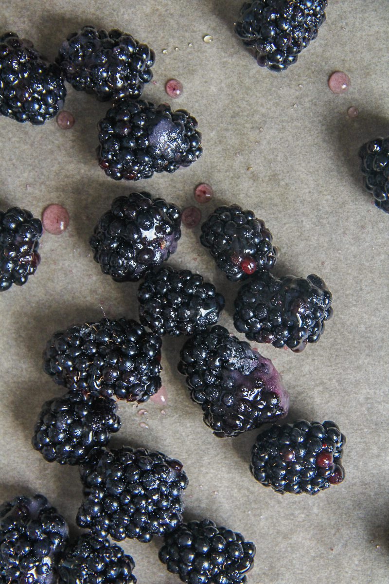 Whole blackberries sit coated in a little sugar on parchment paper.