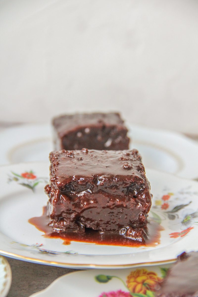 An individual slice of chocolate sauce cake sits on an individual plate.