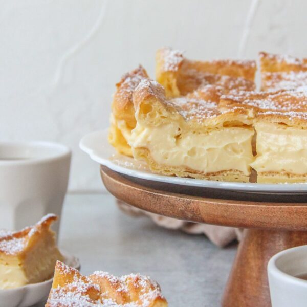 A close up of Karpatka slices on a cake stand with a custard filling.