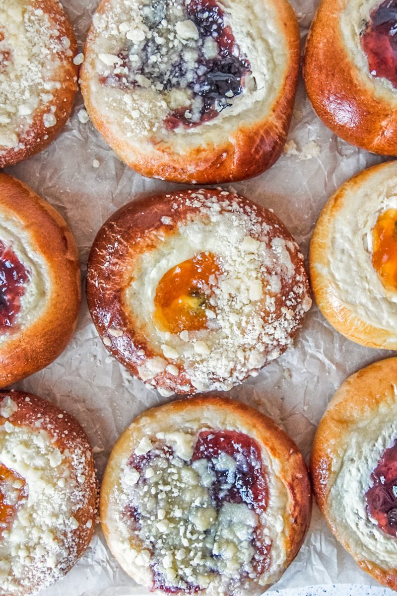 Kolaches with and without streusel toppings sit on parchment paper.