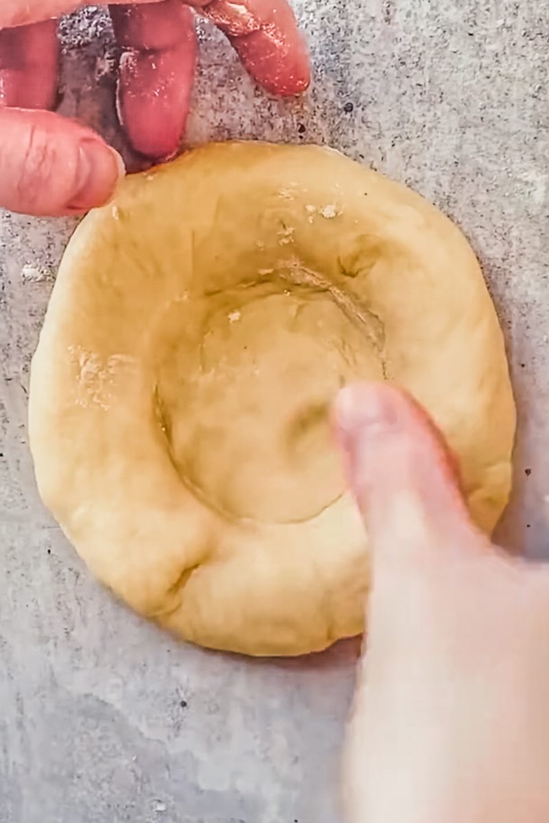 Kolache dough is shaped in the center on a gray surface.