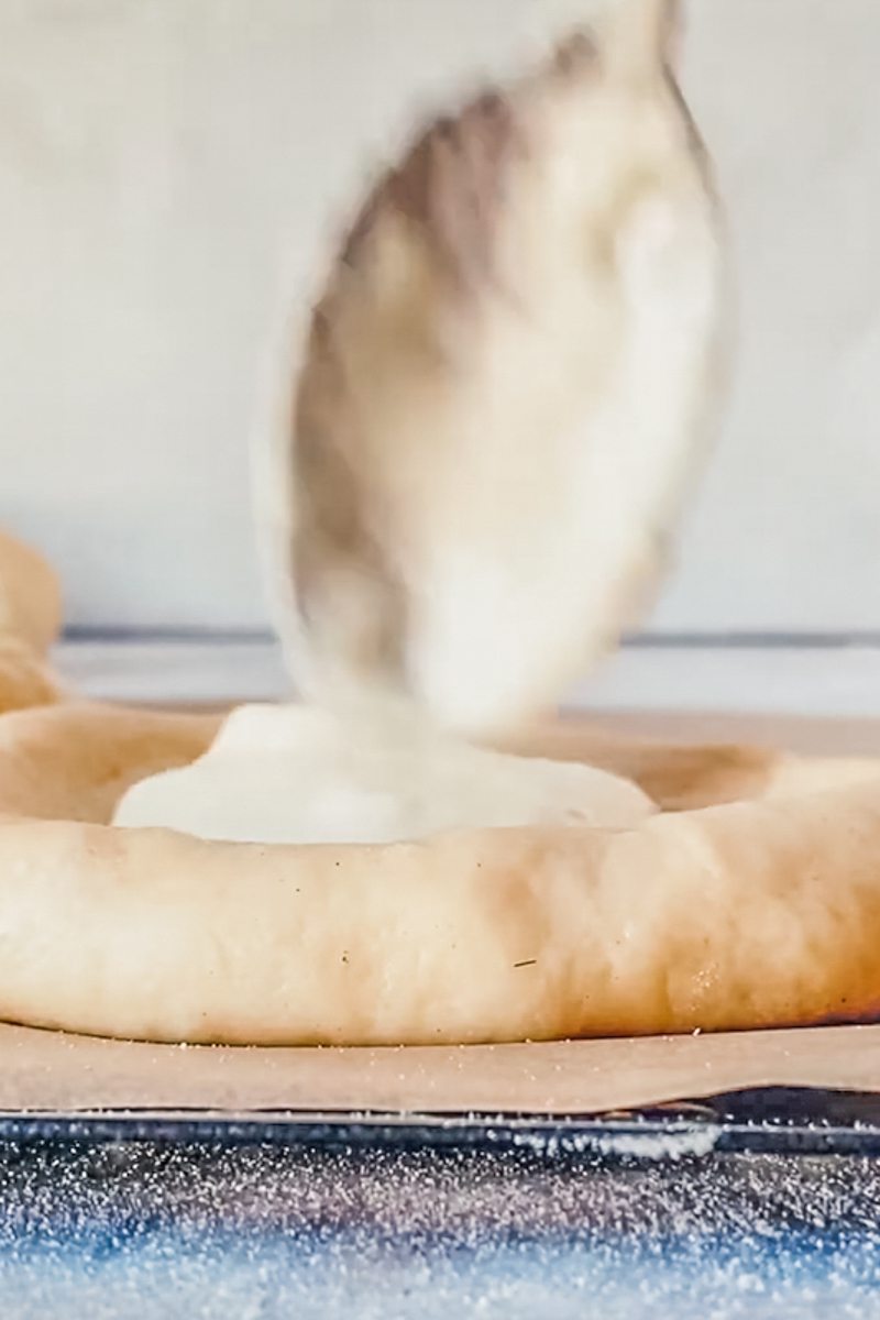 A creamy center is spooned into the center of kolache dough on a gray surface.