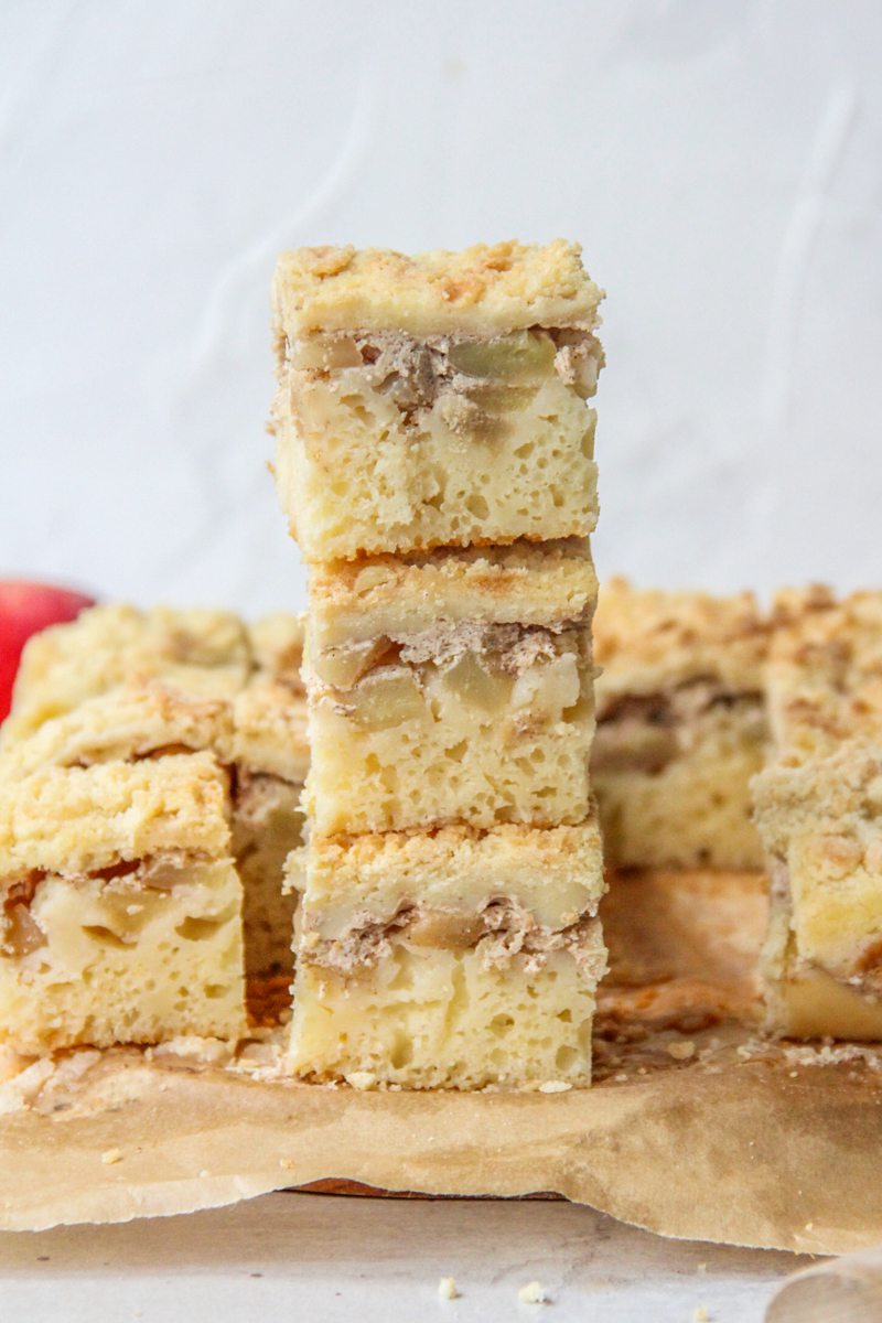 Apple bars sit on top of each other on parchment paper on a gray surface.