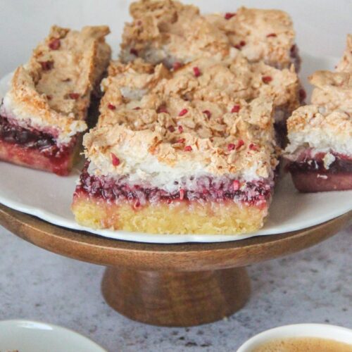 Louise cake slices sit on a cake stand on a white plate on a gray surface.