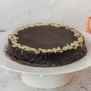 Mazarinkage - Danish Mazarin Cake sits on a white cake stand on a light gray surface.