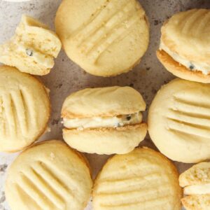 Melting Moments lay on a light gray surface with a few on their side to show off the passionfruit icing.