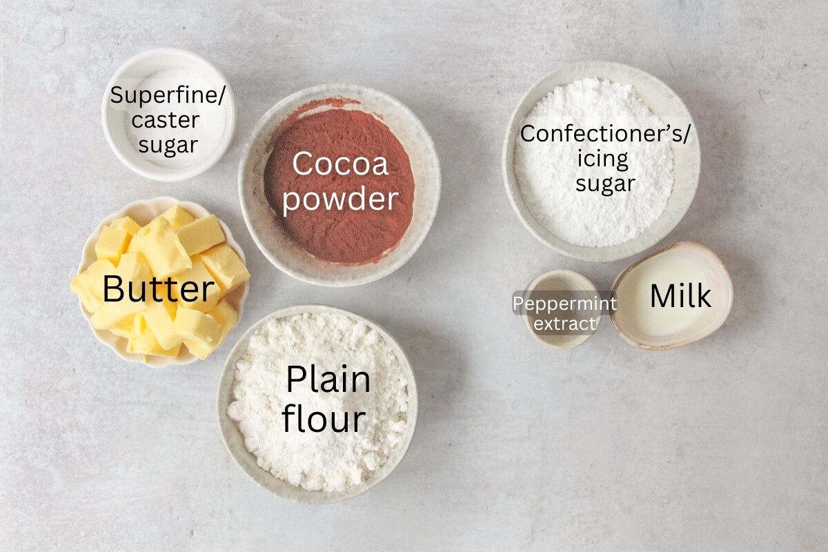 Ingredients for Mint Thumbprint Cookies sit in a series of bowls and plates on a gray surface.