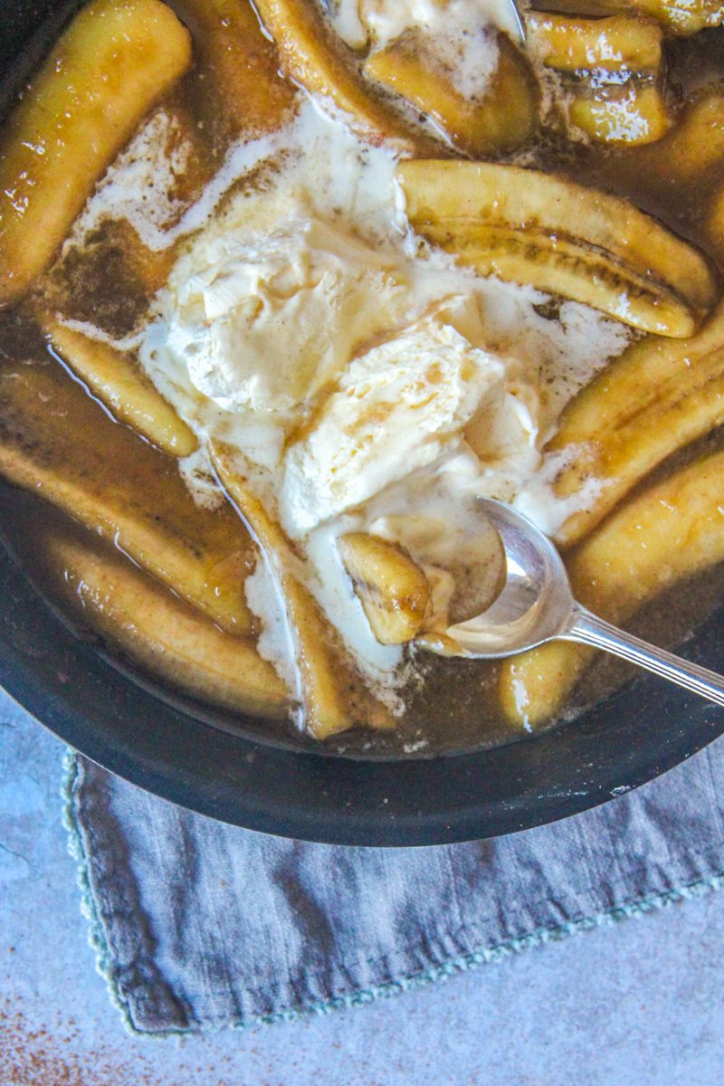 A close up of Banana's Foster and scoops of ice cream in a saucepan on a gray surface.