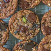 Chocolate oatmeal cookies sit on a metallic cooling rack above a gray surface.