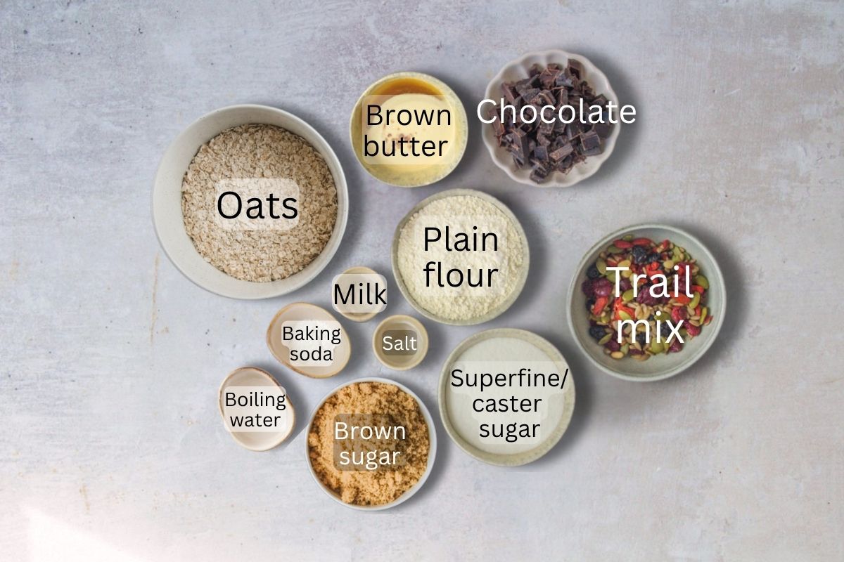 Ingredients for Oatmeal Trail Cookies sit in a series of bowls and plates on a gray surface.