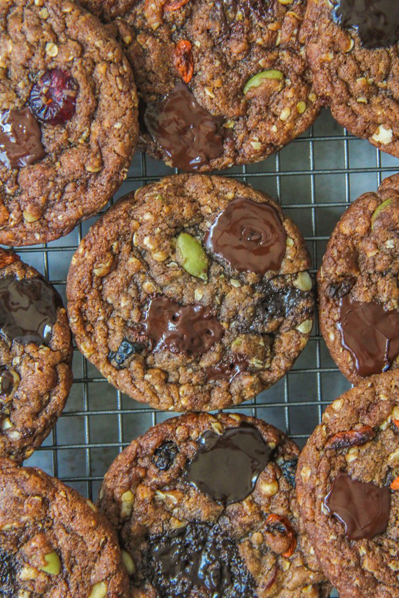 Chocolate oatmeal cookies sit on a metallic cooling rack above a gray surface.