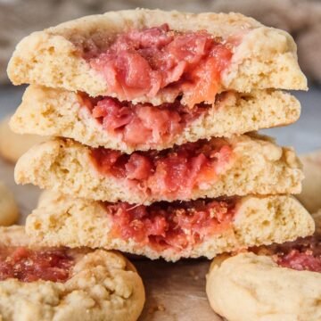 A stack of halved peach muffin cookies sit on top of whole cookies.