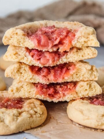 A stack of halved peach muffin cookies sit on top of whole cookies.