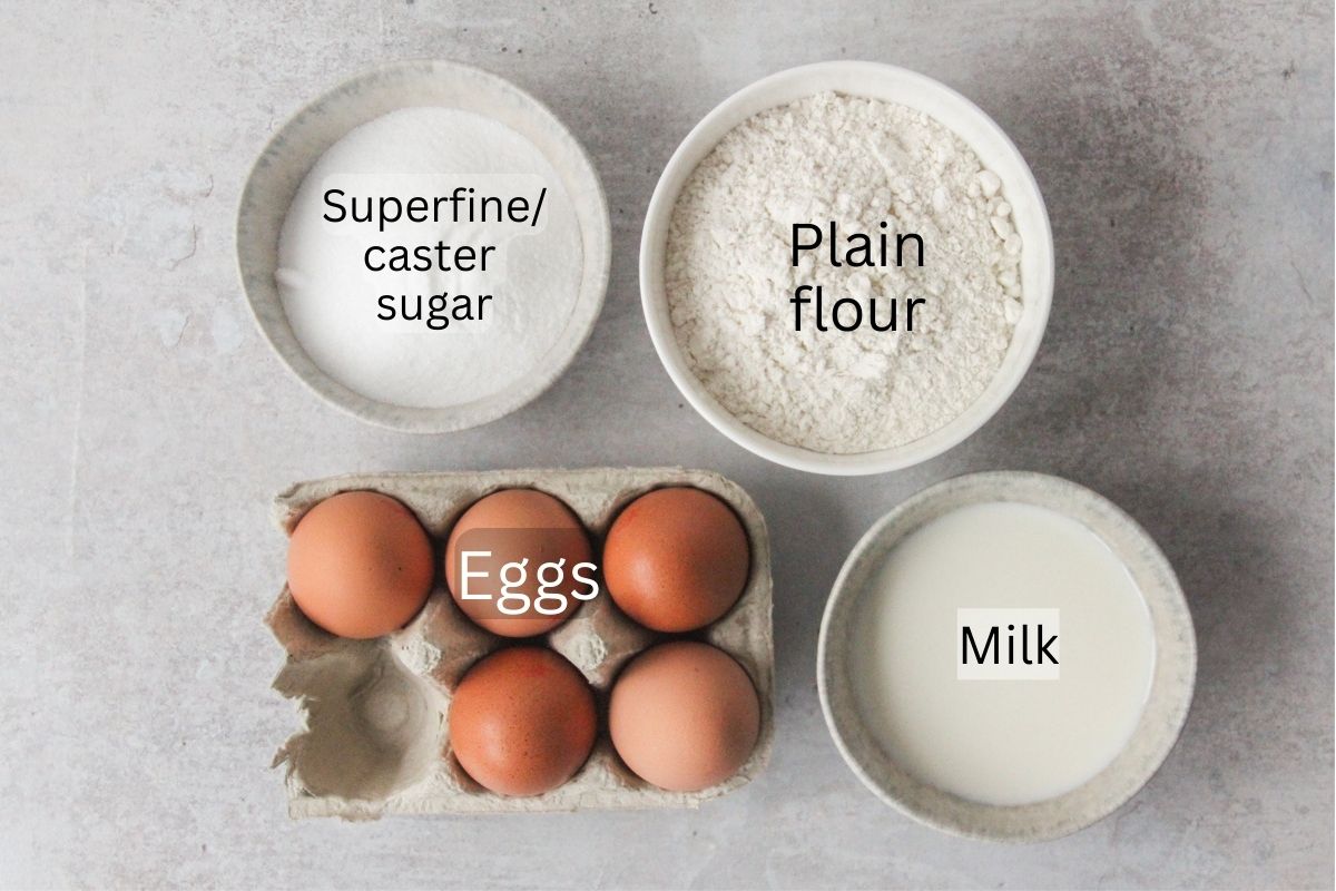 Ingredients for Pfannkuchen - German Pancakes sit in a series of bowls on a gray surface.