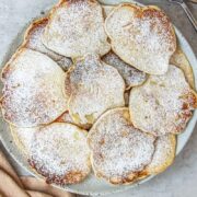 A plate of Polish Apple Pancakes sits on a gray ceramic plate on a gray surface.