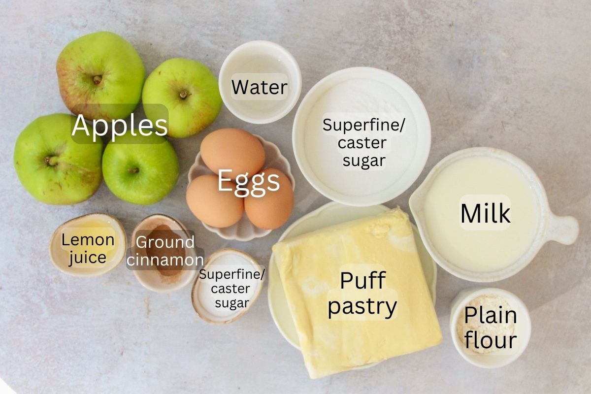Ingredients for Portuguese Apple Tart sit in a series of bowls on a gray surface.