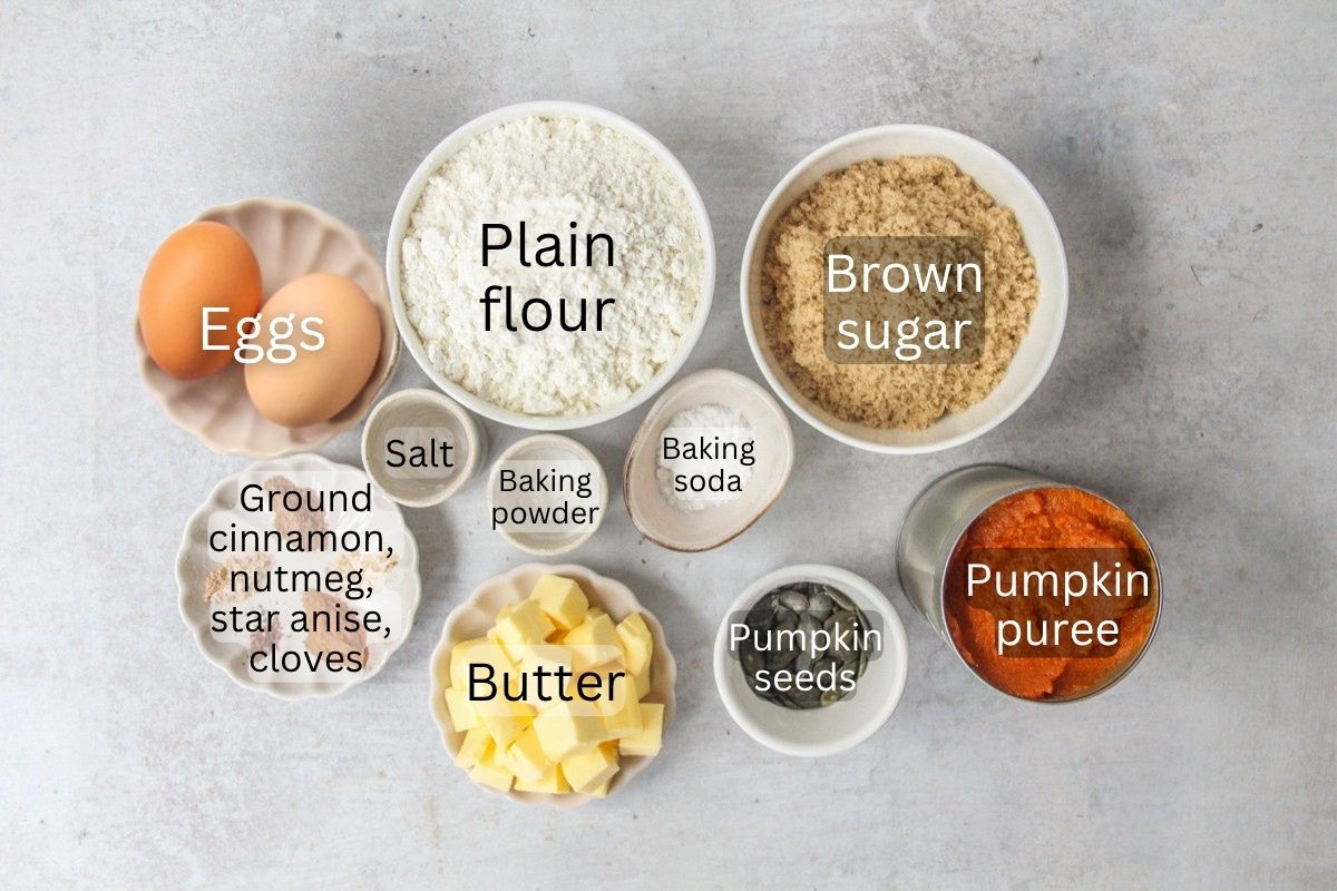 Ingredients for Pumpkin Bread sit in a series of bowls on a gray surface.