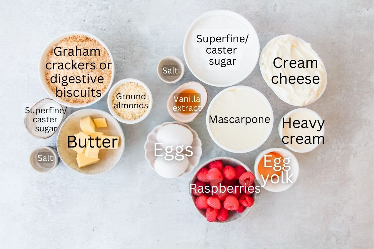 Ingredients for Raspberry Custard Cheesecake sit in a series of bowls on a gray surface.