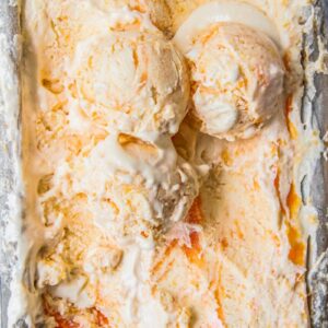 Roasted Peach Semifreddo with three scoops resting on top of the iced dessert sit in a lined rectangle tin.