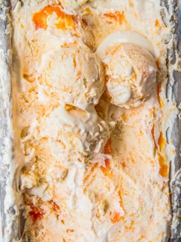 Roasted Peach Semifreddo with three scoops resting on top of the iced dessert sit in a lined rectangle tin.
