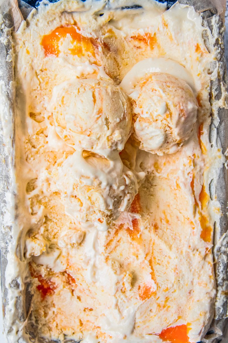 Roasted Peach Semifreddo with three scoops resting on top of the iced dessert sit in a lined rectangle tin.