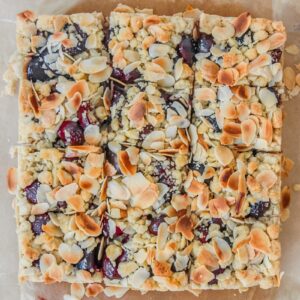 An overhead shot of Latvian Sweet Cherry Crumb Cake sits sliced up on parchment paper.