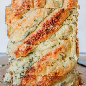 Sliced savory cheese babka sits on it's side with the layers of herbed cheese and brioche on a brown surface.