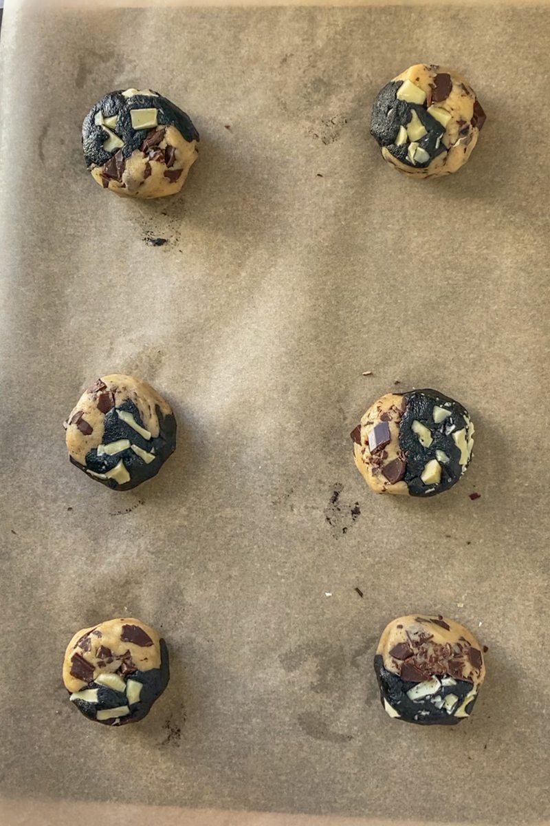 Triple chocolate cookie dough sits on a lined baking tray.