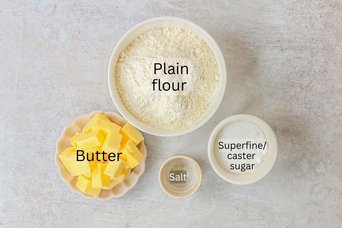 Ingredients for Shortbread sit in a series of bowls and plates on a gray surface.