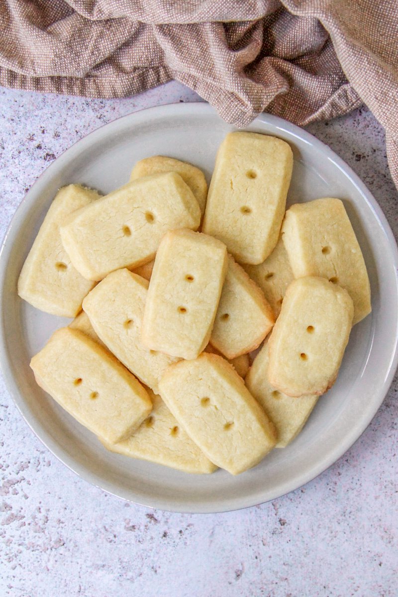 Scottish Shortbread sit on a deep plate on a gray surface with a brown cloth behind.