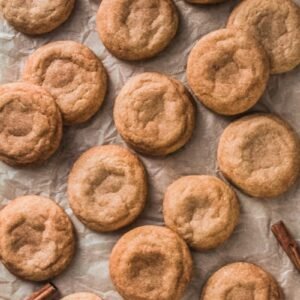 Snickerdoodles sit laid out on parchment paper.