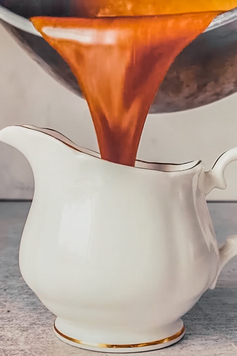 A toffee sauce is poured into a pouring jug on a gray surface.