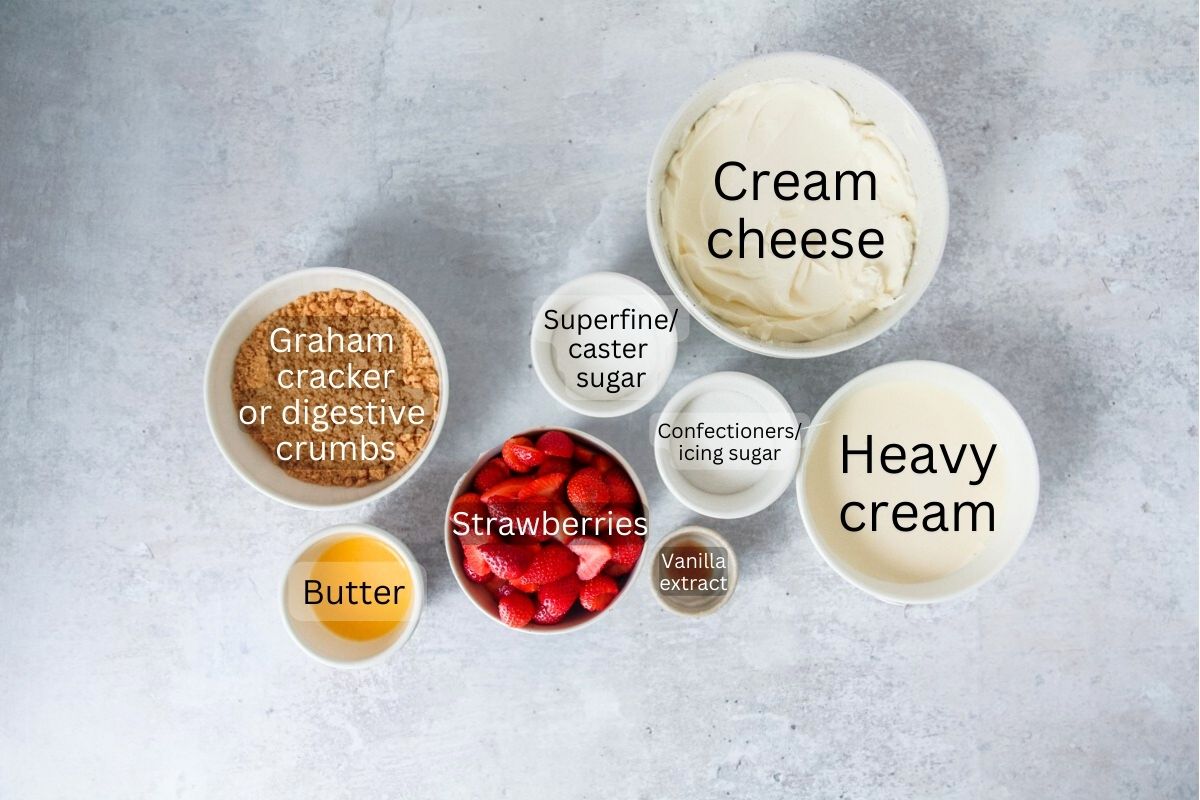 Ingredients for Strawberry Cheesecake sit in a series of bowls on a gray surface.