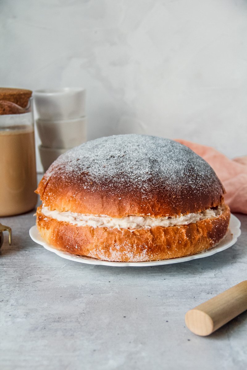 A Sufganiyot Cake or Donut cake sits on a white ceramic bowl on a gray surface.