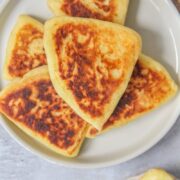 Tattie Scones - Scottish Scones sit stacked on a rimmed gray ceramic plate on a gray surface.