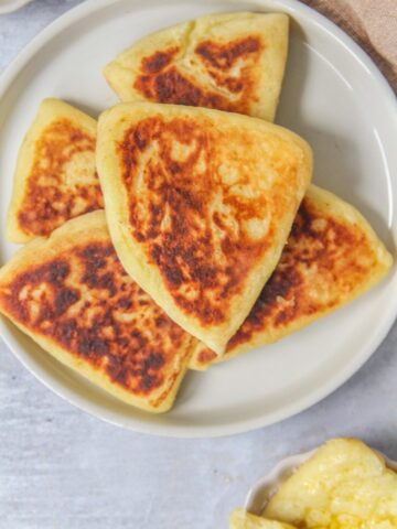 Tattie Scones - Scottish Scones sit stacked on a rimmed gray ceramic plate on a gray surface.