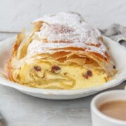 The interior of Topfenstrudel - Austrian Cheesecake Strudel is visible whilst sitting on a white ceramic plate.