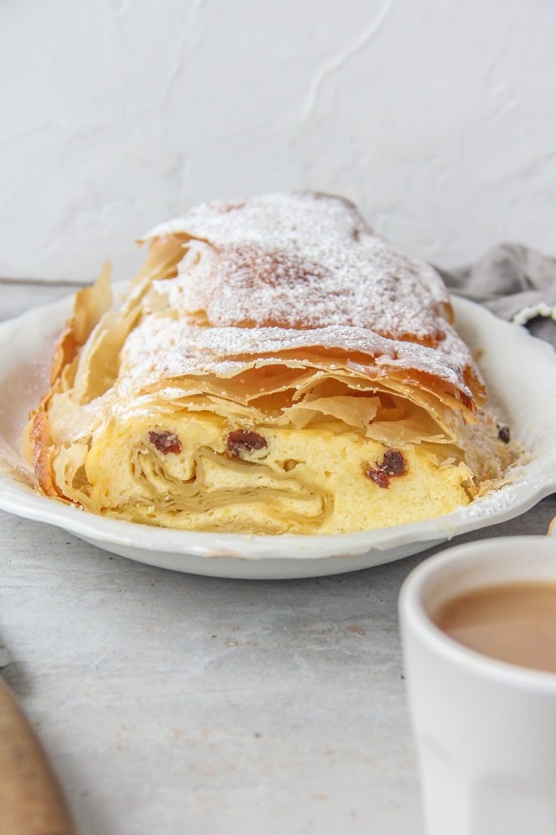 The interior of Topfenstrudel - Austrian Cheesecake Strudel is visible whilst sitting on a white ceramic plate.