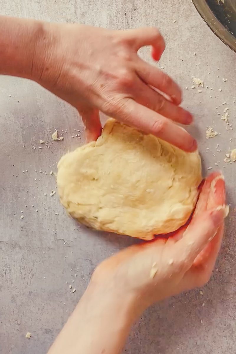 Shortcrust pastry is shaped on a gray surface.