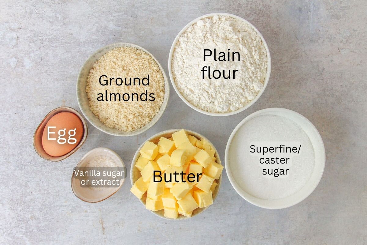 Ingredients for Vanillekranse - Danish Butter Cookies sit in a series of bowls and plates on a gray surface.