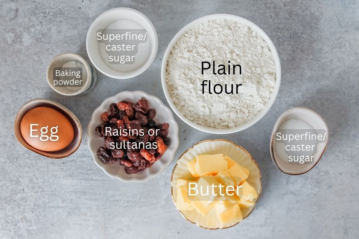 Ingredients for Welsh Cakes sit in a variety of bowls on a gray surface.