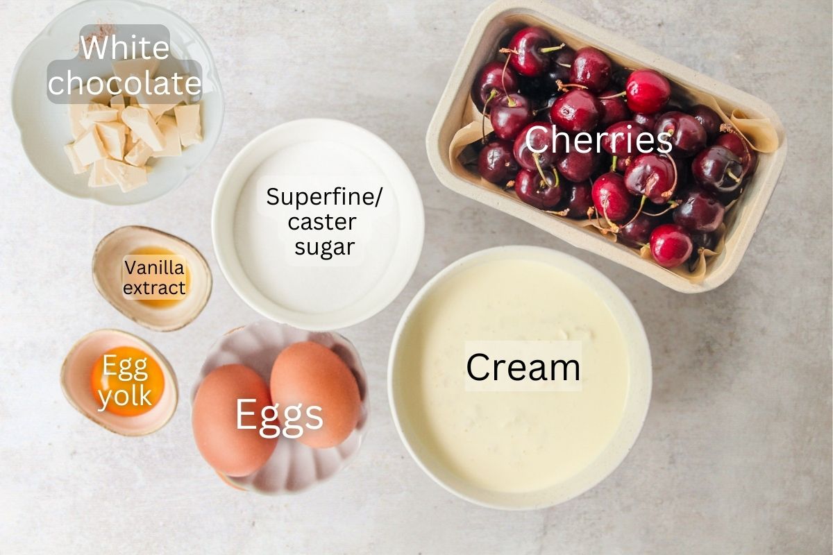 Ingredients for White Chocolate Cherry Semifreddo sit in a series of bowls on a gray surface.