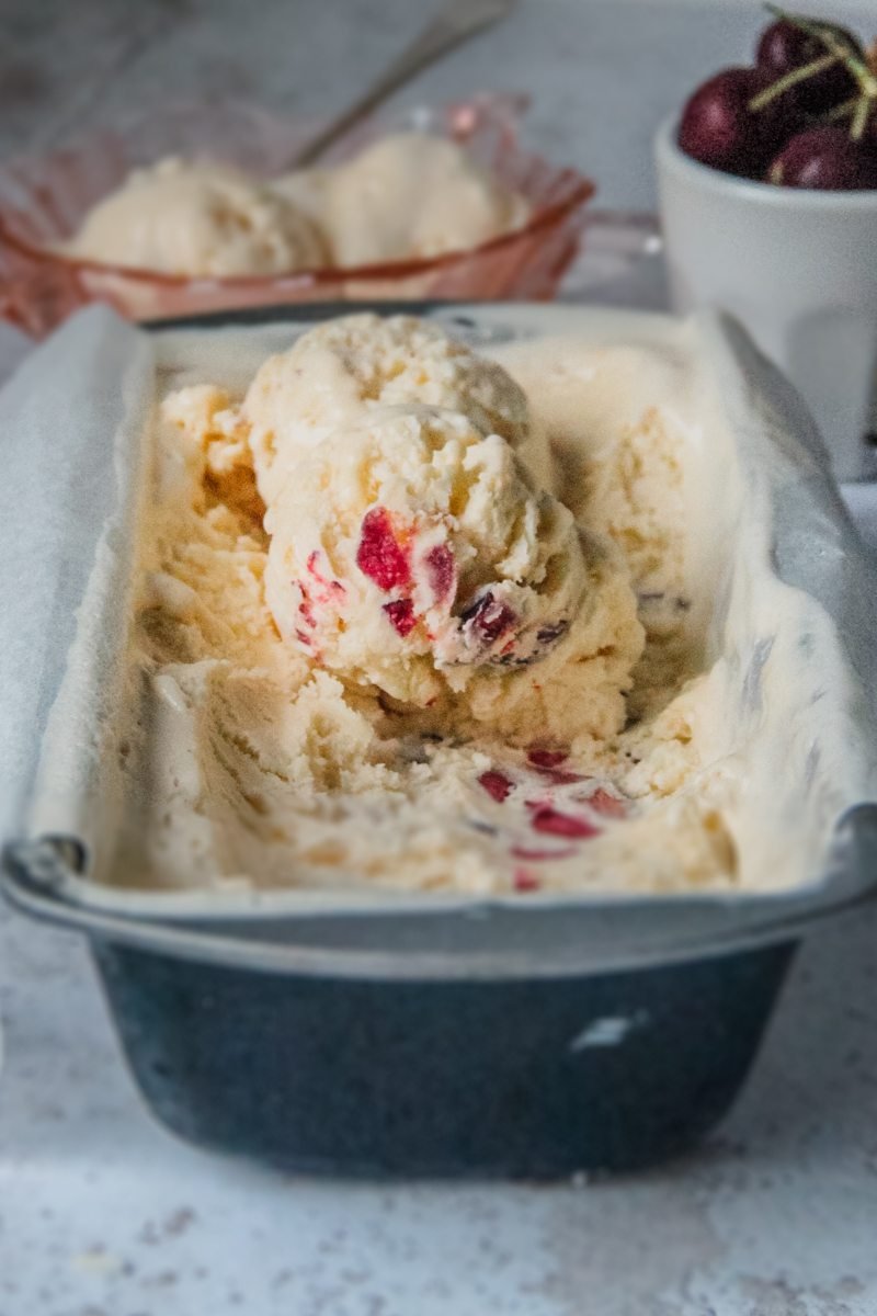 White Chocolate Cherry Semifreddo scoops sit in a metal loaf tin on a light grey background.